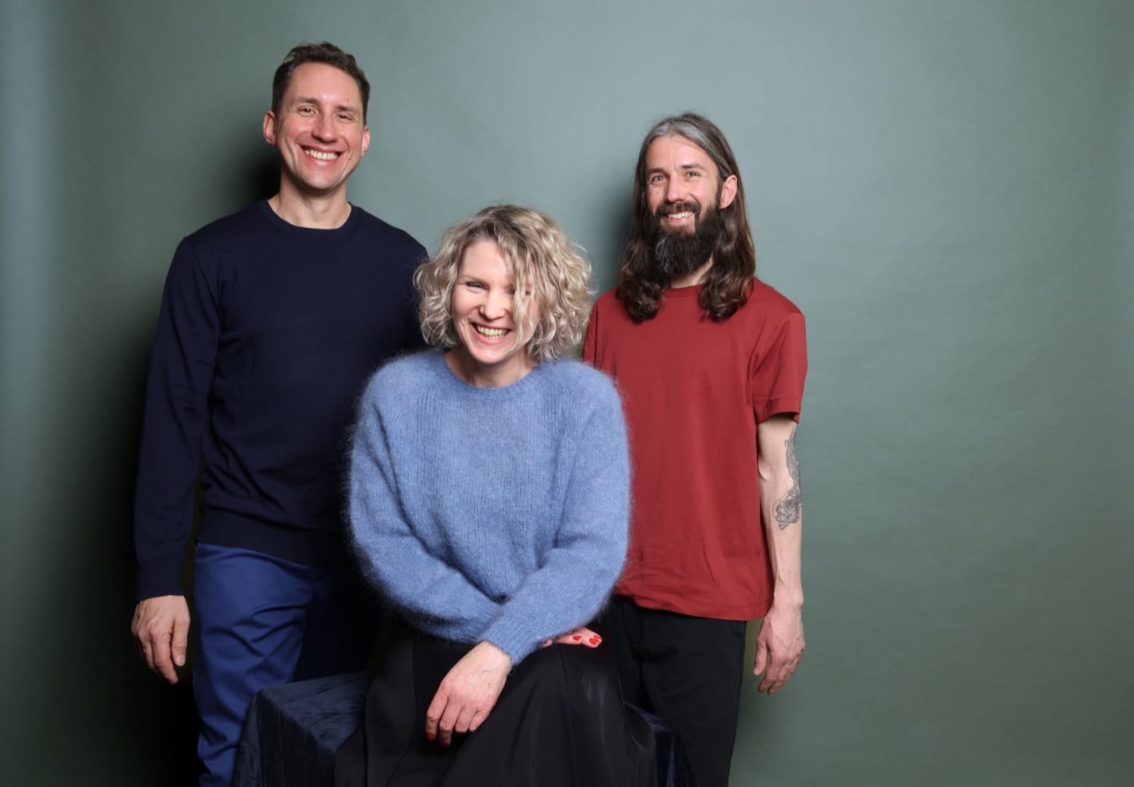 Group portrait of the founders Sascha, Linda and Jonas against a grey-green background
