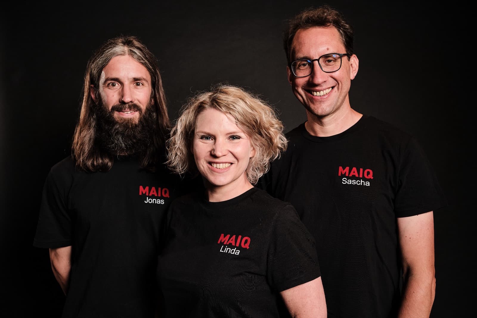 The three founders Jonas, Linda and Sascha in black MAIQ shirts against a dark background